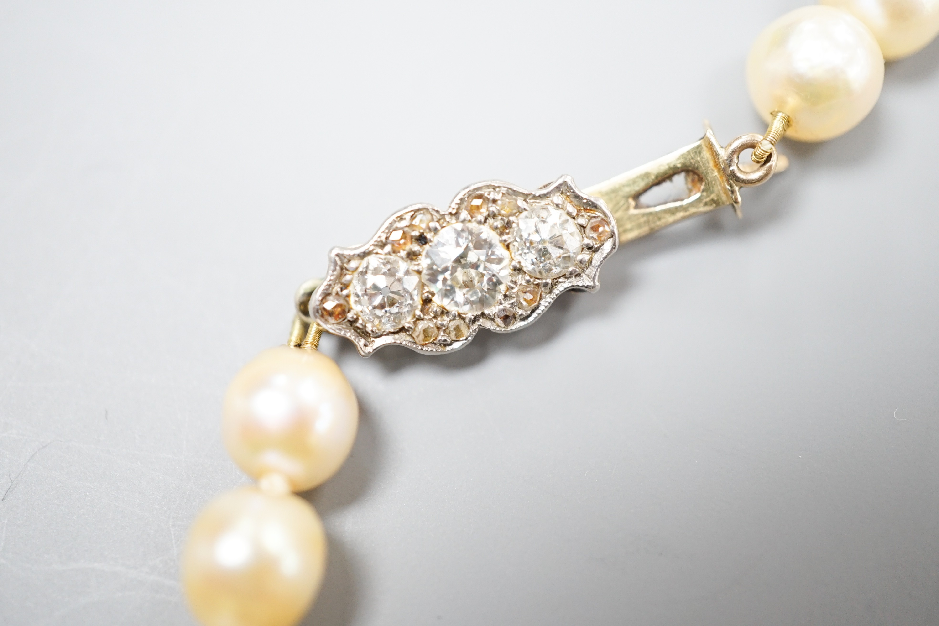 A single strand graduated pearl necklace (not tested for natural), with yellow metal and three stone diamond set clasp, 44cm.